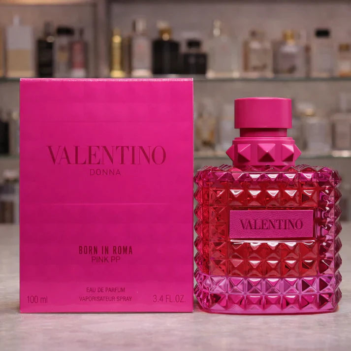 Valentino Donna perfume bottle and packaging in pink on a blurred background of more perfume bottles.