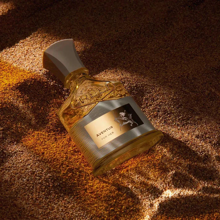 Perfume bottle labeled 'Aventus' on a textured brown surface