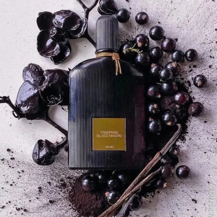 Tom Ford Black Orchid perfume bottle surrounded by dark grapes on a textured surface