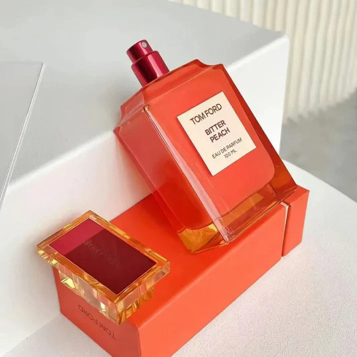 Tom Ford Bitter Peach perfume bottle with red cap on a white surface
